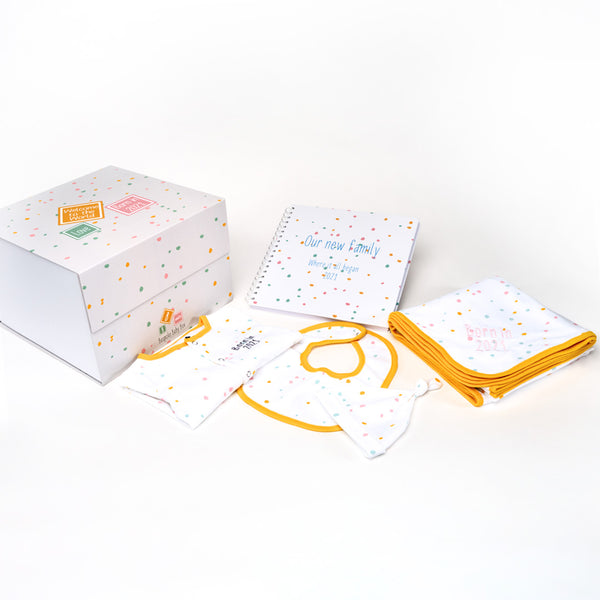 Baby essentials gift box, containing  memory box, memory book, baby blanket, baby grow and bib all with a  neutral dotty pattern with an orange trim that can all be personalised from the Bespoke Baby Box brand