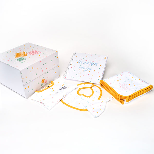 Baby essentials gift box, containing  memory box, memory book, baby blanket, baby grow and bib all with a  neutral dotty pattern with an orange trim that can all be personalised from the Bespoke Baby Box brand  